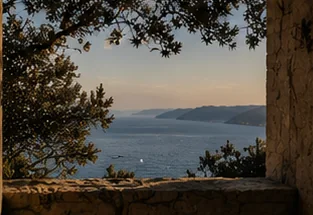 A quiet stone window and olive branches framing a distant sea horizon.
